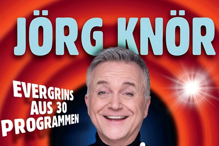 Jörg Knör Roter Hintergrund, Jörg Knör mit Tourtitel "Simply my Best" in der Hand